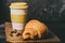 croissant with a mug of coffee on a dark background. retro style with grain
