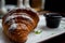 Croissant in powdered sugar on a white plate. apricot jam in a black little plate next to a croissant