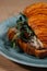 croissant with roast beef, sun-dried tomatoes and butter cream lies on a plate on the table close-up