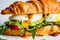 Croissant sandwich with poached egg, tomato and guacamole, closeup. Breakfast food concept