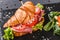 Croissant sandwich with prosciutto, tomatoes, cheese parmesan and greens on black shale board over black stone background