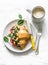 Croissant sandwich with scramble spinach eggs, tomato and cream cheese and coffee on a light background, top view