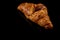 Croissant, a single fresh crispy french Croissant, isolated on a reflective black background