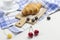 Croissant on white and blue checkered napkin. Cup of coffee cherry and blueberries on table