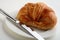 Croissant, white plate and knife