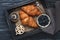 Croissants, cake with blueberries, coffee with marshmallows on a wooden tray with a napkin. Wooden dark background, top view.