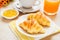 Croissants, coffee cup and juice on wooden table