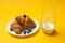 Croissants, milk, flowers and berries on yellow background