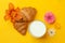 Croissants, milk, flowers  on yellow background