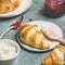 Croissants with raspberry jam, ricotta cheese and milk, square crop