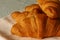 Croissants stacked on a plate with a pink tea towel