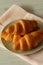 Croissants stacked on a plate with a pink tea towel