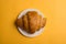 Croissants on a white plate on a yellow background