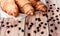 Croissants wrapped in baking paper and spilled coffee beans on wooden table. Top view