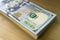 Crolled stack of 100 new dollar bills on wooden background