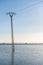 Crooked electrical pylon located in the middle of a flooded rice field