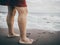 Crop anonymous woman standing on sandy seashore against overcast sky