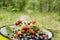 Crop of bilberries and wild strawberries in the can on the forest path