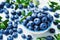 Crop of blueberry or great bilberry in bowl on blue wooden table. Organic superfood and healthy nutrition.