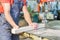 Crop carpenter cutting wooden piece on workbench