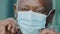 Crop closeup of mature man putting on protective surgical facial mask, african american elderly retired in medical