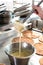 Crop cook pouring cream in bowl. Crop woman holding ladle and stirring sweet gentle cream