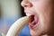 Crop girl with mouth open eating fresh peeled banana