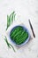 Crop of green or string beans in vintage bowl and knife on white stone background top view. Organic and diet food.