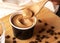 Crop image of hand scooping coffee ice cream in a paper cup with a wooden spoon on a wooden cutting board with messy coffee beans.