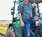 Crop image of mature farmer standing on tractor at field