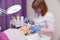 Crop master applying white mask with brush on face and neck of young woman in towel lying on table