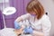 Crop master applying white mask with brush on face and neck of young woman in towel lying on table