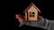 Crop person with wooden toy house on black background. Top view of crop anonymous person holding small wooden toy house