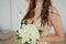 Crop photo of bride in beautiful golden dress with wedding bouquet of white roses in hands, close up