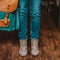 Crop photo of young woman feet girl traveler in jeans and boots with backpack indoors