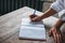 Crop photo of young woman  in white shirt with pen and planner doing hand notes at table