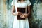 Crop shot of an unrecognizable woman wearing a white dress and holding a book in her hands.li