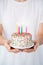 Crop shot of a woman holding a birthday cake with lighted candles in her hands. With Copy space. Concept of birthday and