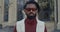 Crop view of bearded man turning head and looking to camera while standing at city street. Portrait of mixed race man