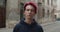Crop view of depressed guy with dyed red hair looking to camera. Portrait of hipster millennial man with earring wearing