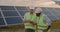 Crop view of diverse male engineers standing at solar farm and discussing efficient plan of construction. Two men in