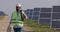 Crop view of male bearded engineer carrying cabel and case . Mixed race man in hard helmet and uniform walking at solar