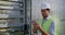 Crop view of male electrical engineer standing near therminal box of solar panel. Guy in protective helmet and uniform