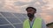 Crop view of mixed raced male engineer in uniform. Bearded man in hard helmet walking at solar power plant for