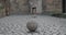 Crop view of teenager boy lacing his shoes, running and kicking ball at old city street. Focus on ball. Concept of