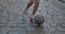Crop view of teenager feet dribbling at empty old city street with paving stones. Person in sneakers running and kicking
