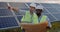 Crop view of two male businessmen standing at solar farm and discussing plans. Men in hard helmet and uniform talking