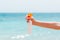 Croped image of woman`s hand holding sunblock spray at the beach