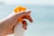 Croped image of woman`s hand holding sunscreen spray at the sea background