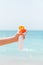 Croped image of woman`s hand holding sunscreen spray at the sea background